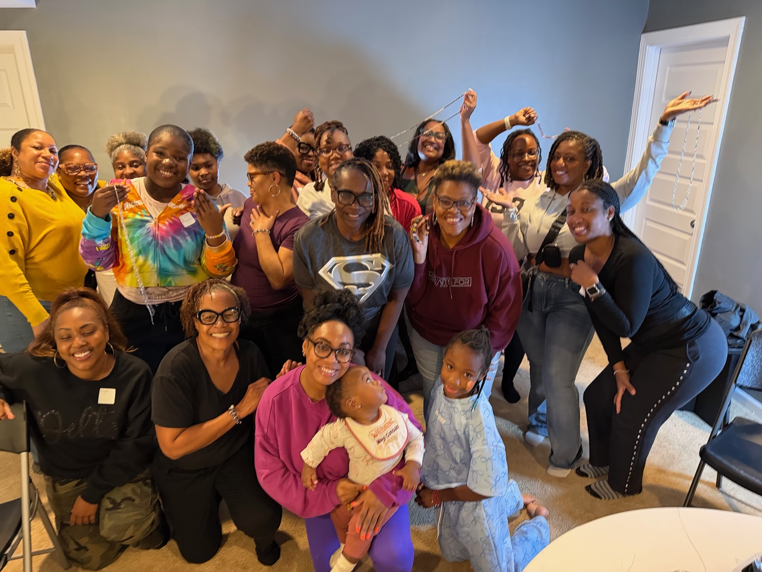 A celebratory group photo of Sacred Beads guests holding up their finished jewelry.