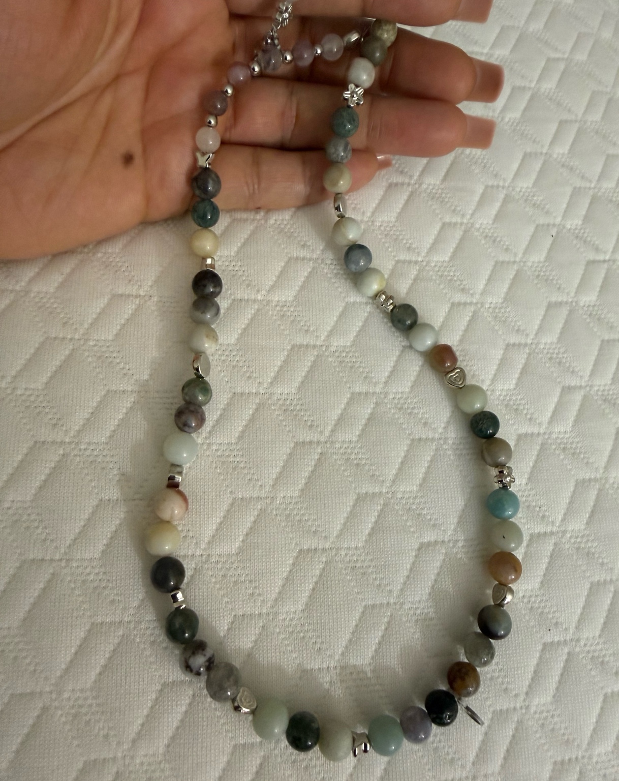 A hand holding a multicolored beaded necklace at Sacred Beads.