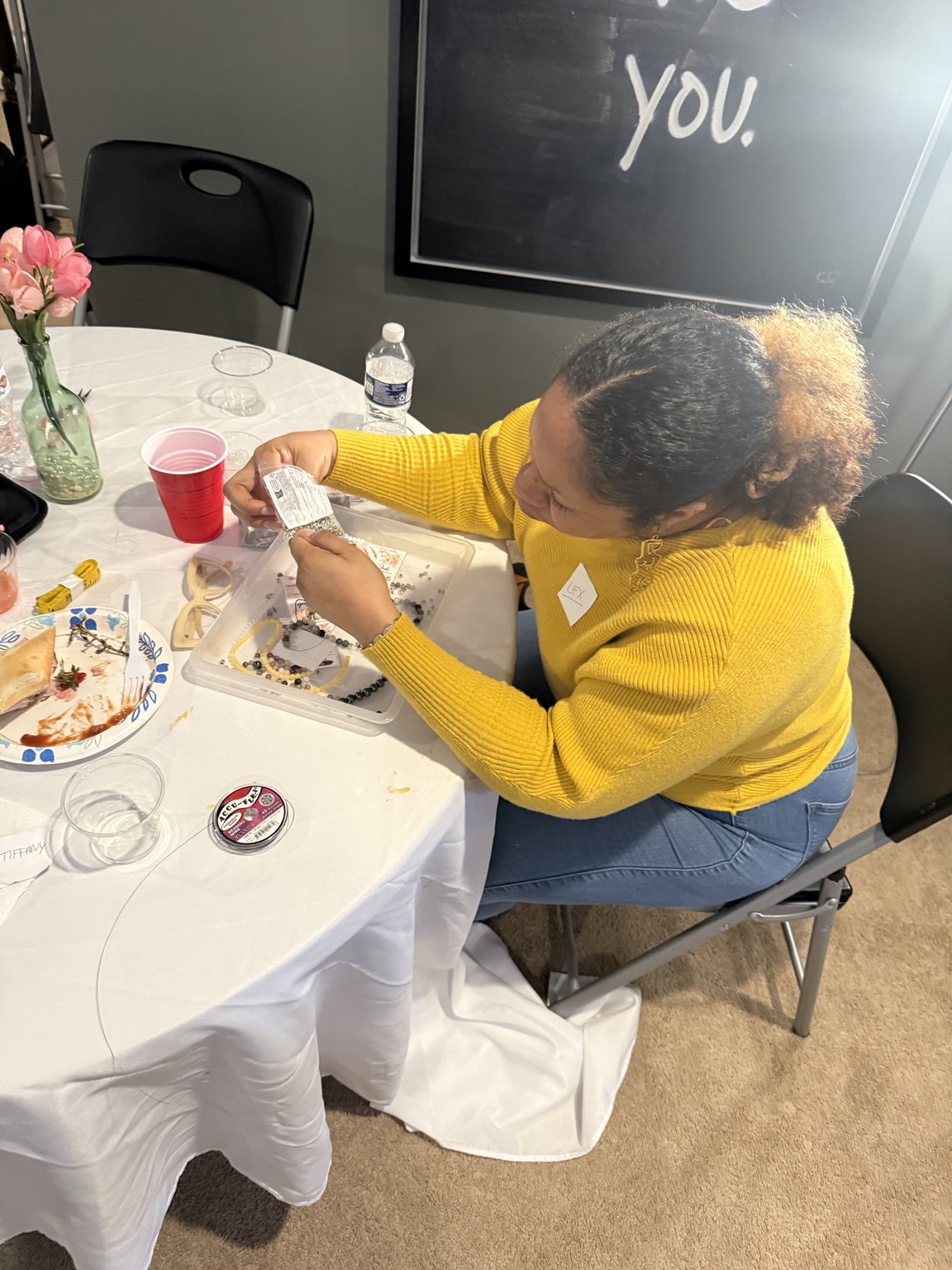 A participant in a yellow sweater working with beads at Sacred Beads.