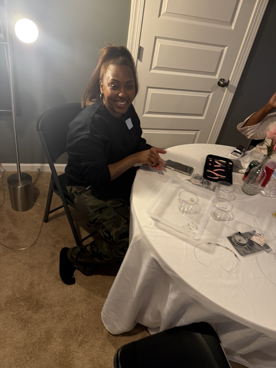 A smiling Sacred Beads participant seated beside jewelry-making supplies.
