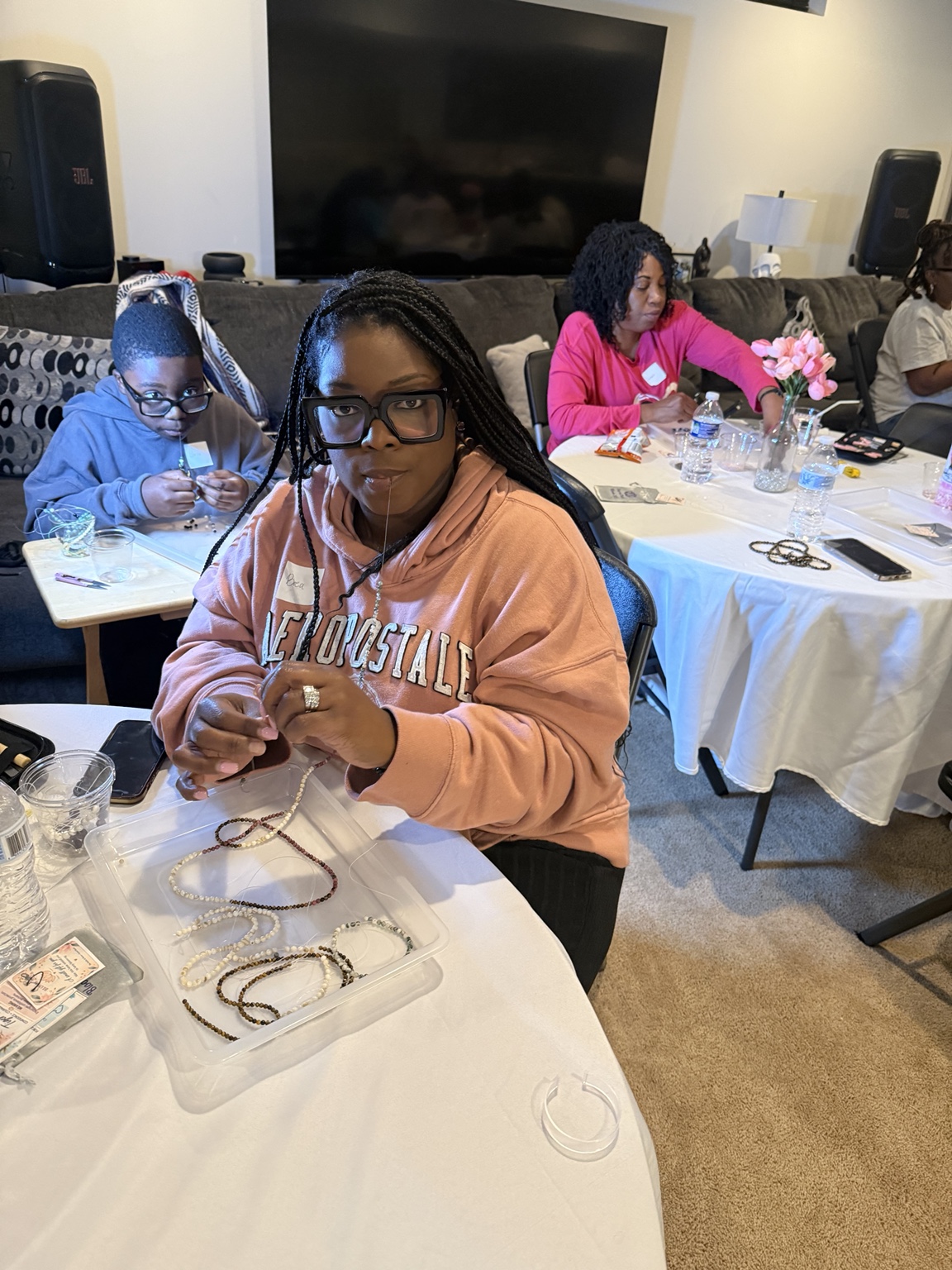 A Sacred Beads participant stringing beads at a table with other guests.