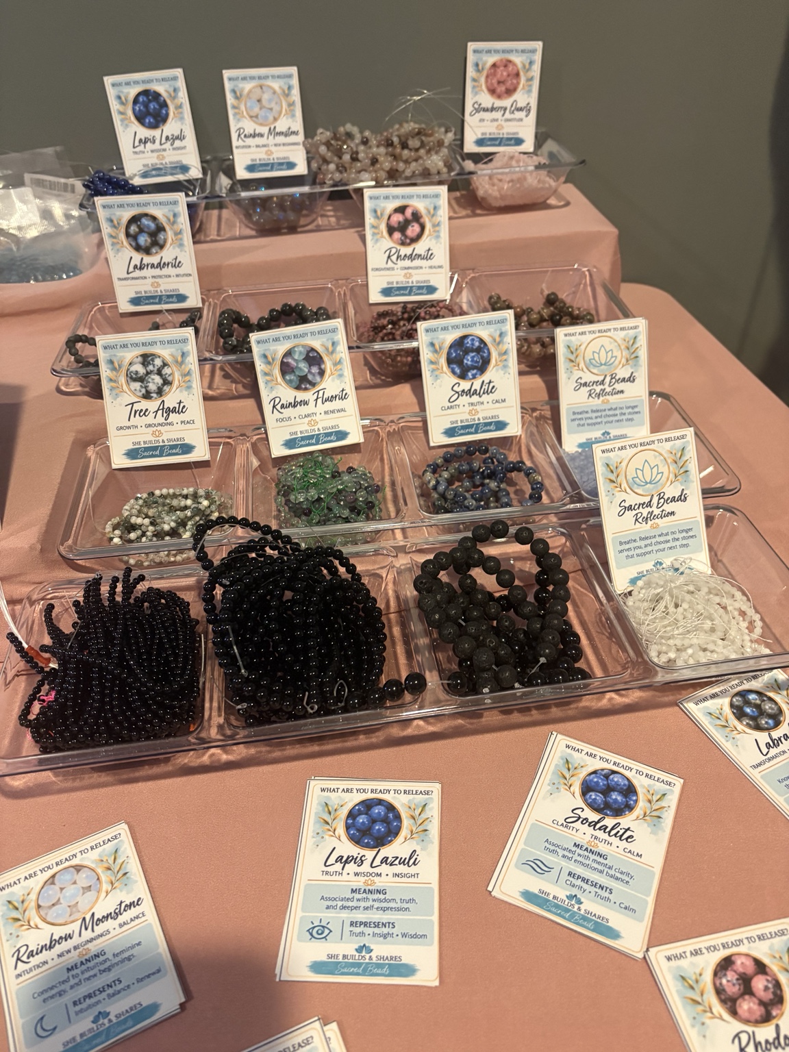 Jewelry-making beads arranged in trays alongside information cards.