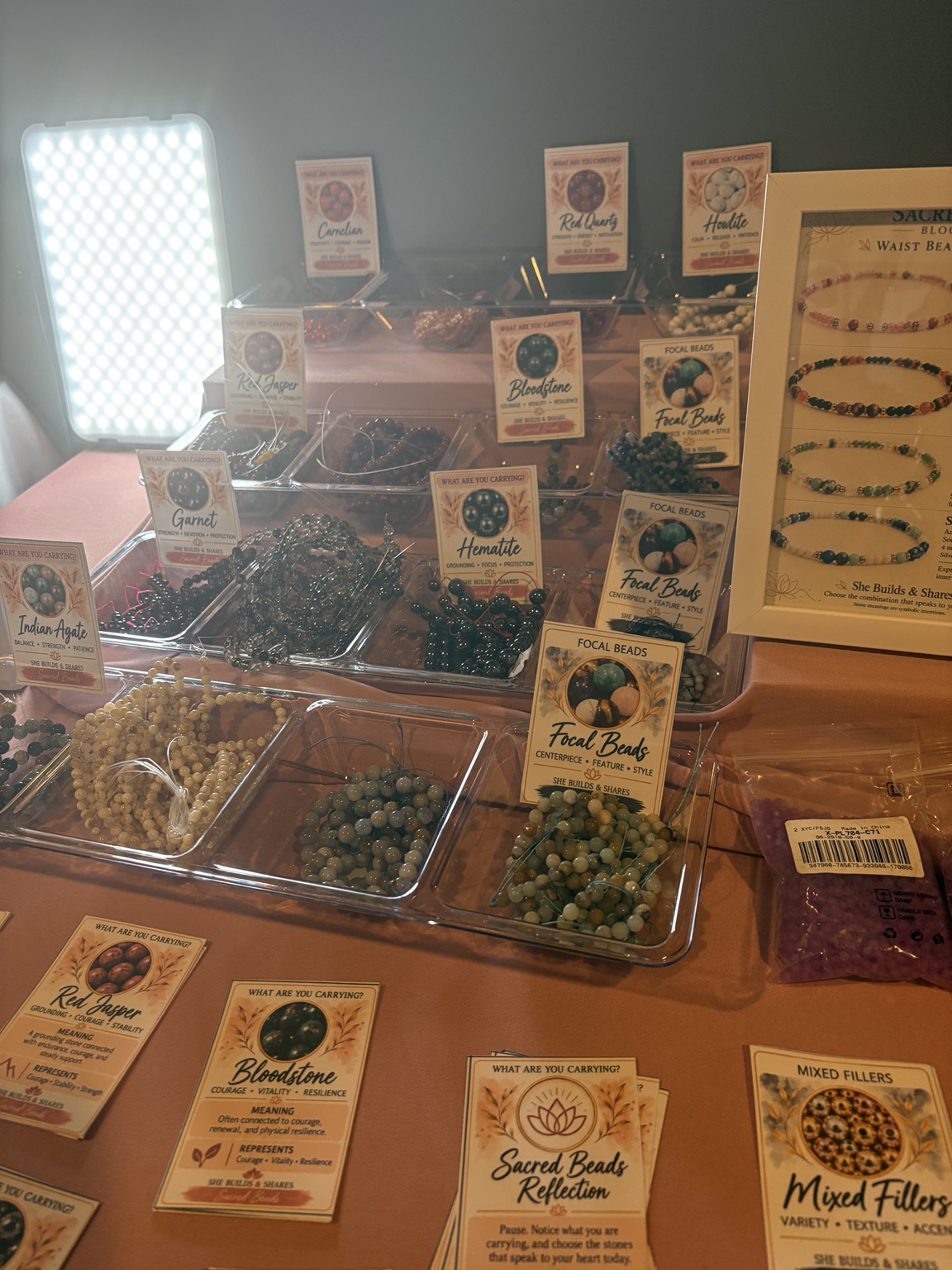 Trays of colorful beads and information cards on the Sacred Beads workshop table.